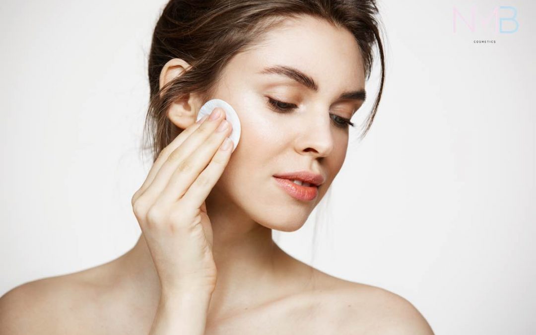Mujer limpiando la piel de su cara con un disco desmaquillador