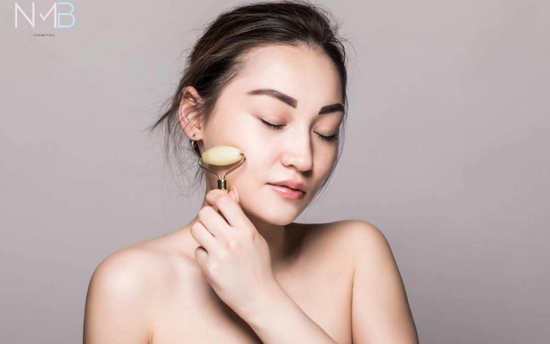 Mujer asiática pasando un rodillo de jade por su rostro